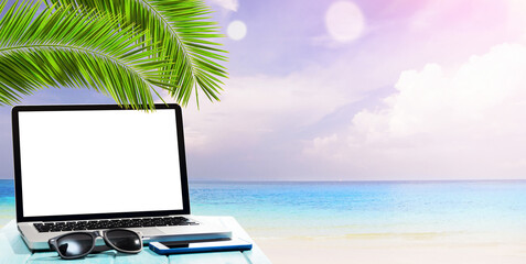 Modern laptop on blue wooden table with blank screen at tropical beach