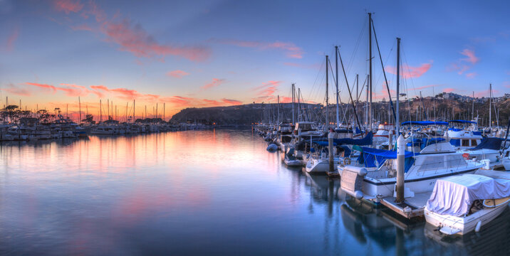 Sunset over sailboats in the calm water of the Dana Point harbor in Southern California, USA