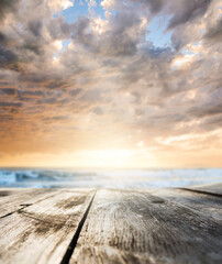 Obraz premium Wooden table and sunset at seaside. Focus on table, blurred background.