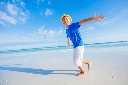 Cute kid boy in yellow hat having fun on sea beach