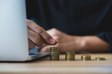 Money saving and finance concept. Businessman using hand stack money on a wooden table. He saving the money for the future, education, investment and retirement.