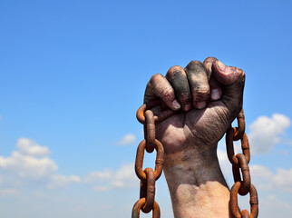 Rusty iron chain in human male right hand against the blue sky - Powered by Adobe