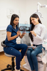 diagnosis with x-ray images, female doctor explaining treatment to her patient, clinic interior,...
