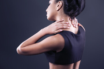 Fototapeta premium Body pain. Studio shot of beautiful young woman with dark brown hair. Woman suffering from neck ache