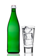 Green bottle of sparkling mineral water with glass nd ice cubes on white background