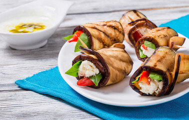 rolls of grilled slices of eggplant with feta cheese and tomato with Tzatziki sauce, close-up
