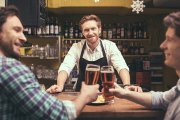 Football time. Friends spending time together in pub. Guys having fun while drinking beer. Barman looking at camera