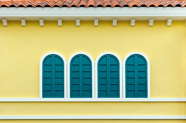 Four green arched windows on yellow wall of the house in Italy retro style