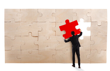 Businessman complete a puzzle inserting a missing piece