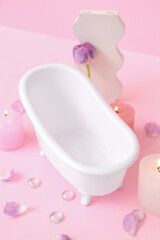 Obraz na płótnie Canvas Small bathtub, burning candles and decor on pink background