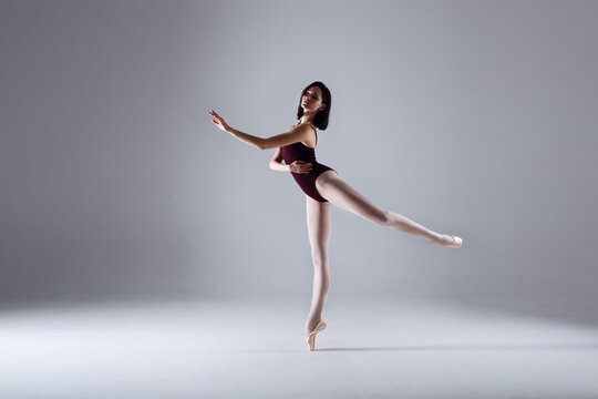 Slim ballerina is dancing in the white studio in the contrast light