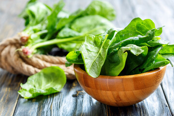Spinach leaves in a bowl on an old wooden stool, selective focus.