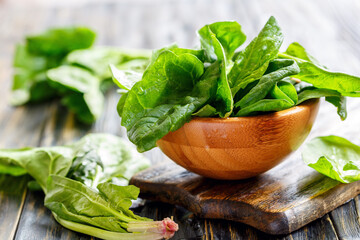 Bowl of fresh spinach leaves on an old kitchen table, selective focus.