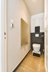 a modern bathroom with black and white tiles on the walls, toilet in the fore - doord corner next...
