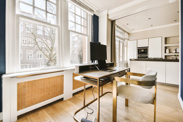 a living room with a desk, chair and television set in the middle of the room on the right side