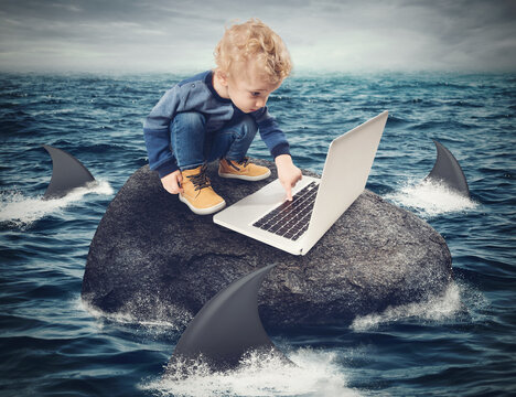 Child looks at the computer on a rock surrounded by sharks