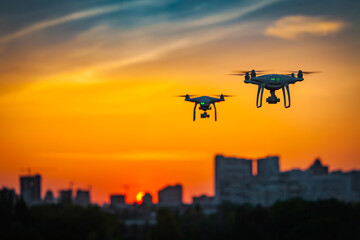 Two drone quad copters with high resolution digital camera flying aerial over spectacular sunset...