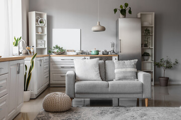 Interior of light kitchen with stylish fridge, counters, sofa and shelving units