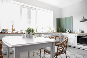 Interior of light kitchen with counters, table and chairs