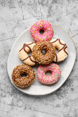 Plate with sweet donuts on grey grunge background