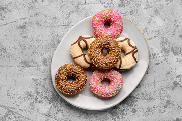 Plate with sweet donuts on grey grunge background
