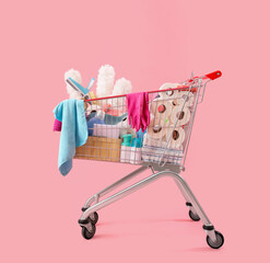 Shopping cart full of cleaning supplies on pink background