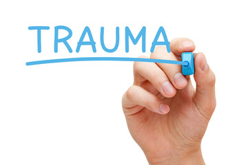 Hand writing Trauma with blue marker on transparent wipe board.