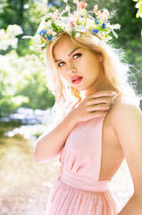 beautiful woman with pretty makeup and pink lipstick posing outdoors wearing spring and summer dress and flower crown