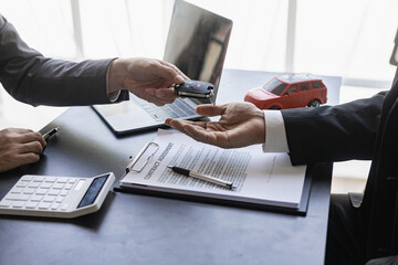 Car rental service concept. Close up view Hand of agent giving car key to customer after signed...