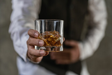 Young man holding glass of whiskey drinking alcohol at counter in pub Man's hand pouring whiskey into glass