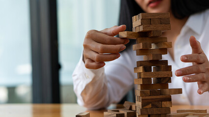 Young woman placing wooden blocks on tower, business plan and strategy, risk concept to grow business with jengka wooden blocks - obrazy, fototapety, plakaty