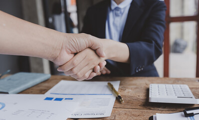 Business woman shaking hands and finishing up meeting at desk in office.