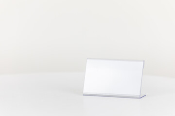 A white business card holder placed on a white table. mockup