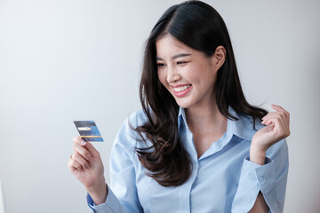 Cheerful Asian woman with smart phone and credit card, she fills in credit card information to pay for goods and services, online shopping concept pay by credit card via smartphone.