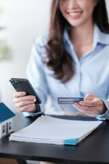Close up Asian woman with smart phone and credit card, she fills in credit card information to pay for goods and services, online shopping concept pay by credit card via smartphone.