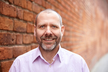 Portrait of smiling man against a brick wall background.