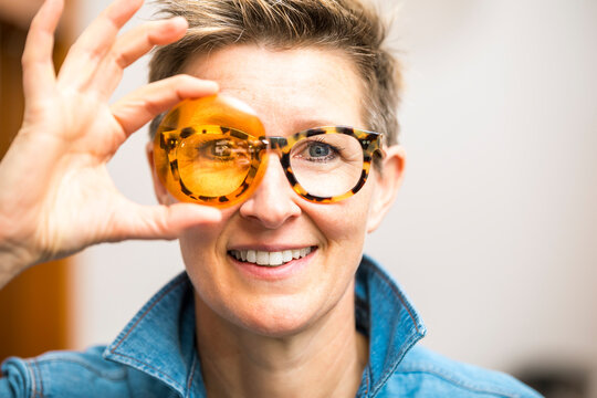 An image of a woman with glasses looking through orange glass