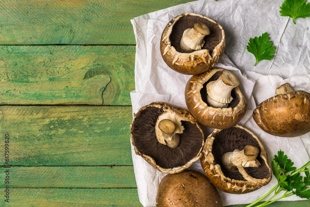 Sticker fresh uncooked brown mushrooms and parsley leaves branch on rustic wooden green painted background.