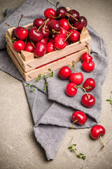 Red ripe cherries in small wooden box on kitchen countertop.