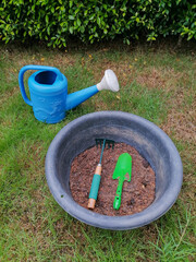 Green gardening tools are shovels and rakes placed in the soil pan. The background image is trees, leaves, lawns.