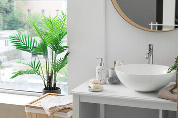 Fototapeta premium Table with sink bowl and bath accessories in interior of light bathroom