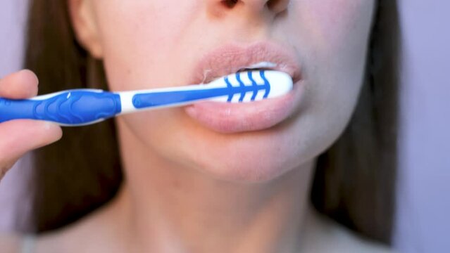 Woman brushes her teeth with toothbrush with toothpaste close-up, front view