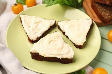 Plate of tasty sandwiches with cream cheese on green wooden background
