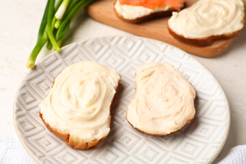 Obraz na płótnie Canvas Plate of tasty sandwiches with cream cheese on light background