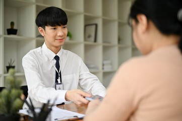 A professional Asian male banker meeting with a female client in the office.