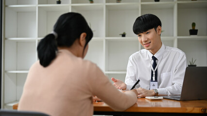 A professional Asian male banker meeting with a female client in the office.