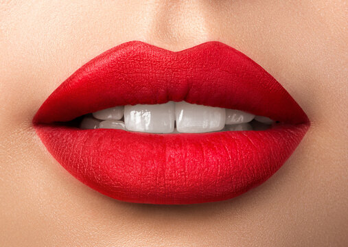 Close up view of beautiful woman lips with purple matt lipstick. Open mouth with white teeth. Cosmetology, drugstore or fashion makeup concept. Beauty studio shot. Passionate kiss