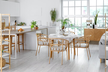 Obraz premium Interior of light open space kitchen with served dining table, island and big window