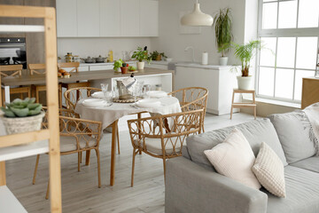 Fototapeta na wymiar Interior of light open space kitchen with grey sofa, served dining table and island
