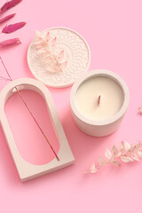 Holder with candle and decorative podium on pink background